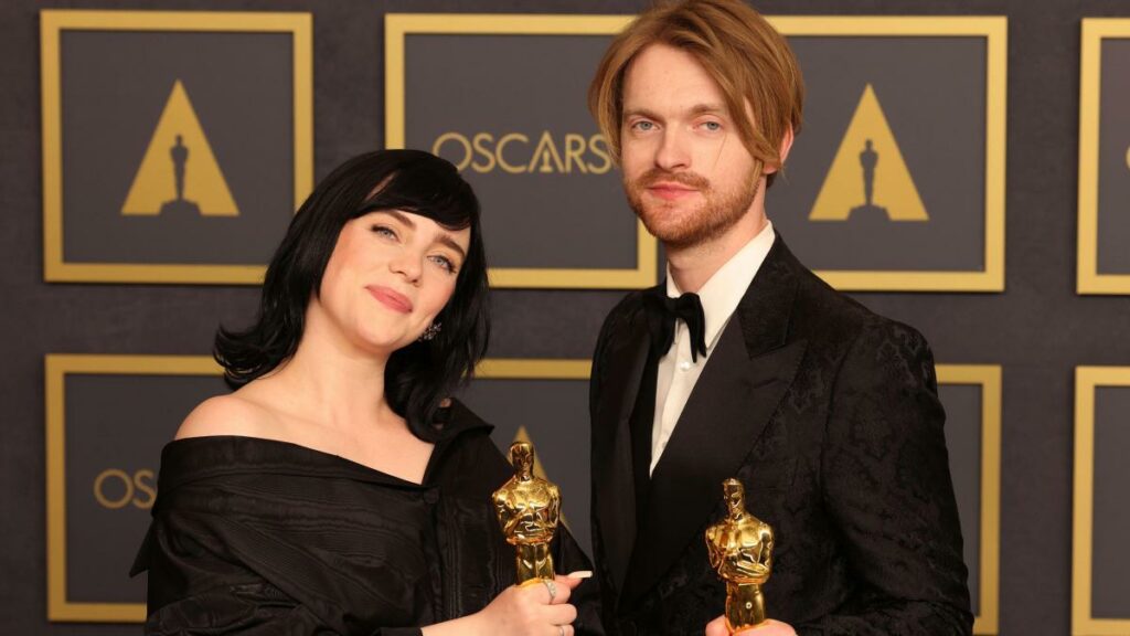 Billie Eilish y Finneas posando con sus premios Óscar.
